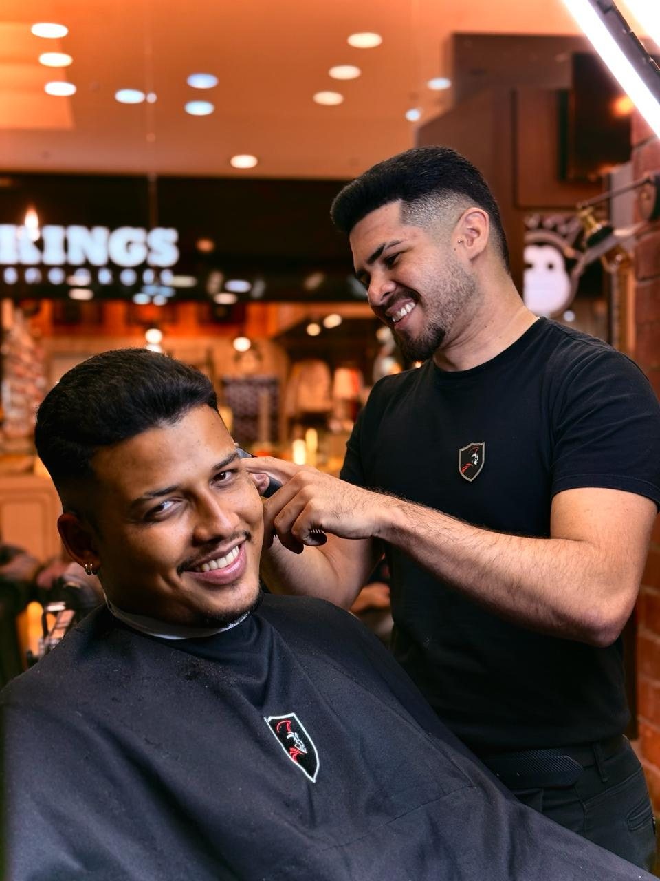 Barbeiro da Rede Trezentos finalizando o corte de um cliente sorridente